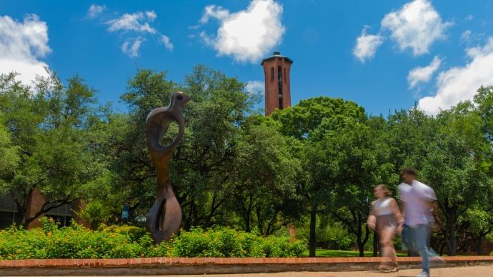 A landscape shot of the Coates Esplanade with students walking by on the left, the "Large Interior Form" statue on the right, and the Tower in the distance